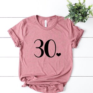 May include: A dusty rose colored t-shirt with the number 30 and a small heart printed on the front.