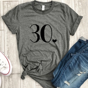 May include: Gray t-shirt with the number 30 and a small heart printed on the front.