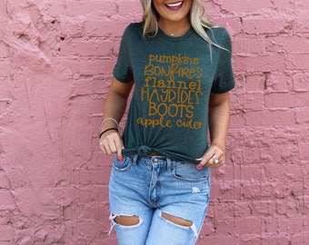 May include: A green t-shirt with the text "pumpkins, bonfires, flannel, hayrides, boots, apple cider" in orange lettering.