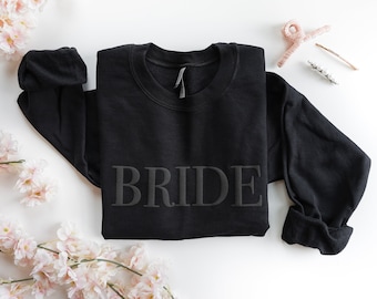 May include: Black sweatshirt with the word "BRIDE" in raised lettering.