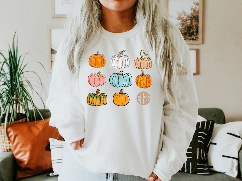 May include: White sweatshirt with a colorful pumpkin design and the monogram "EGG" printed on the front.
