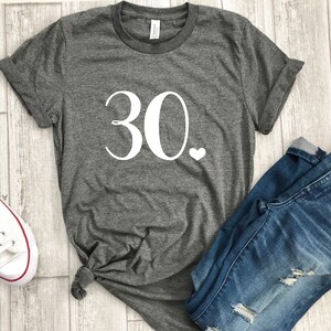 May include: Gray t-shirt with white text that says "30." and a small white heart.