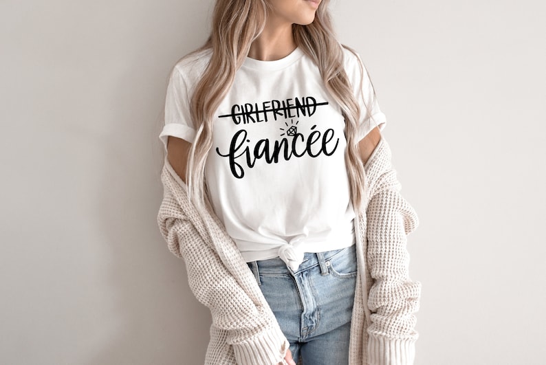 May include: A white t-shirt with the text "Girlfriend - Fianc&eacute;e" and a diamond ring graphic.