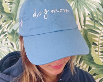 May include: A light blue baseball cap with the text "dog mom" embroidered in white on the front.
