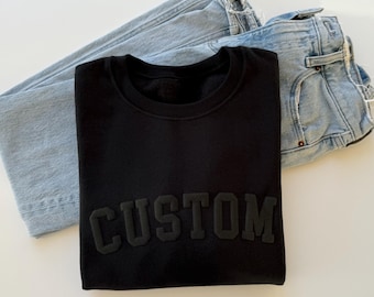 May include: Black sweatshirt with the word "CUSTOM" in raised lettering.