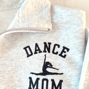 May include: Grey sweatshirt with a black graphic of a dancer and the text "DANCE MOM".