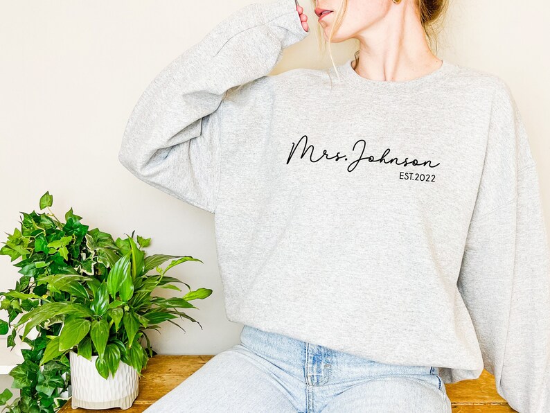May include: Gray sweatshirt with the text "Mrs. Johnson EST. 2022" in black script font.