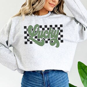 May include: A gray sweatshirt with a green "Lucky" graphic on a black and white checkered background.