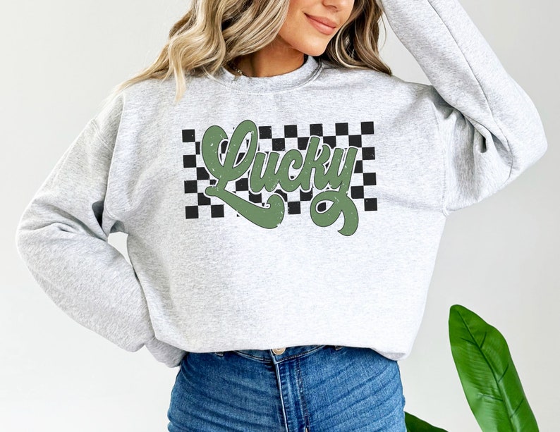 May include: A gray sweatshirt with a green "Lucky" graphic on a black and white checkered background.