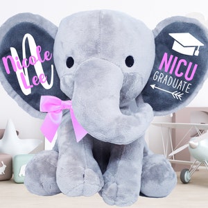 May include: Gray plush elephant with pink bow, personalized with the name "Nicole Lee" on one ear and "NICU GRADUATE" with a graduation cap on the other ear.