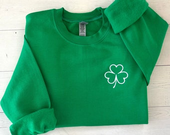 May include: Green sweatshirt with a white four-leaf clover embroidered on the front.