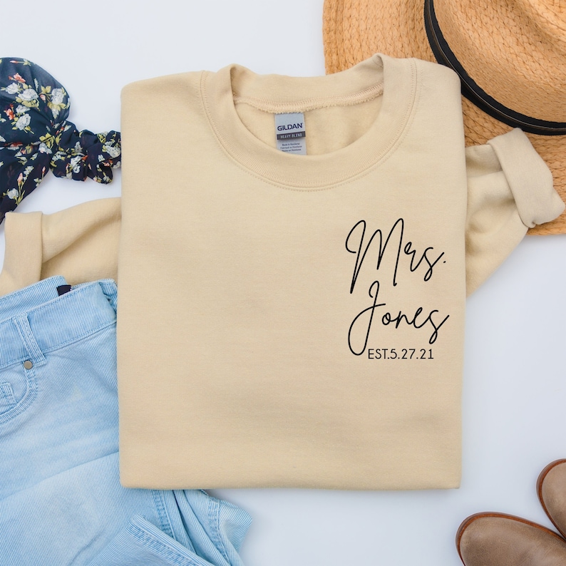 May include: A beige sweatshirt with the text "Mrs. Jones EST. 5.27.21" printed on the front.