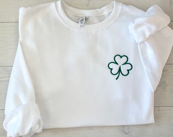 May include: White sweatshirt with a green embroidered shamrock on the left chest. The long sleeves are cuffed. The sweatshirt is made of a soft material and is perfect for St. Patrick's Day.