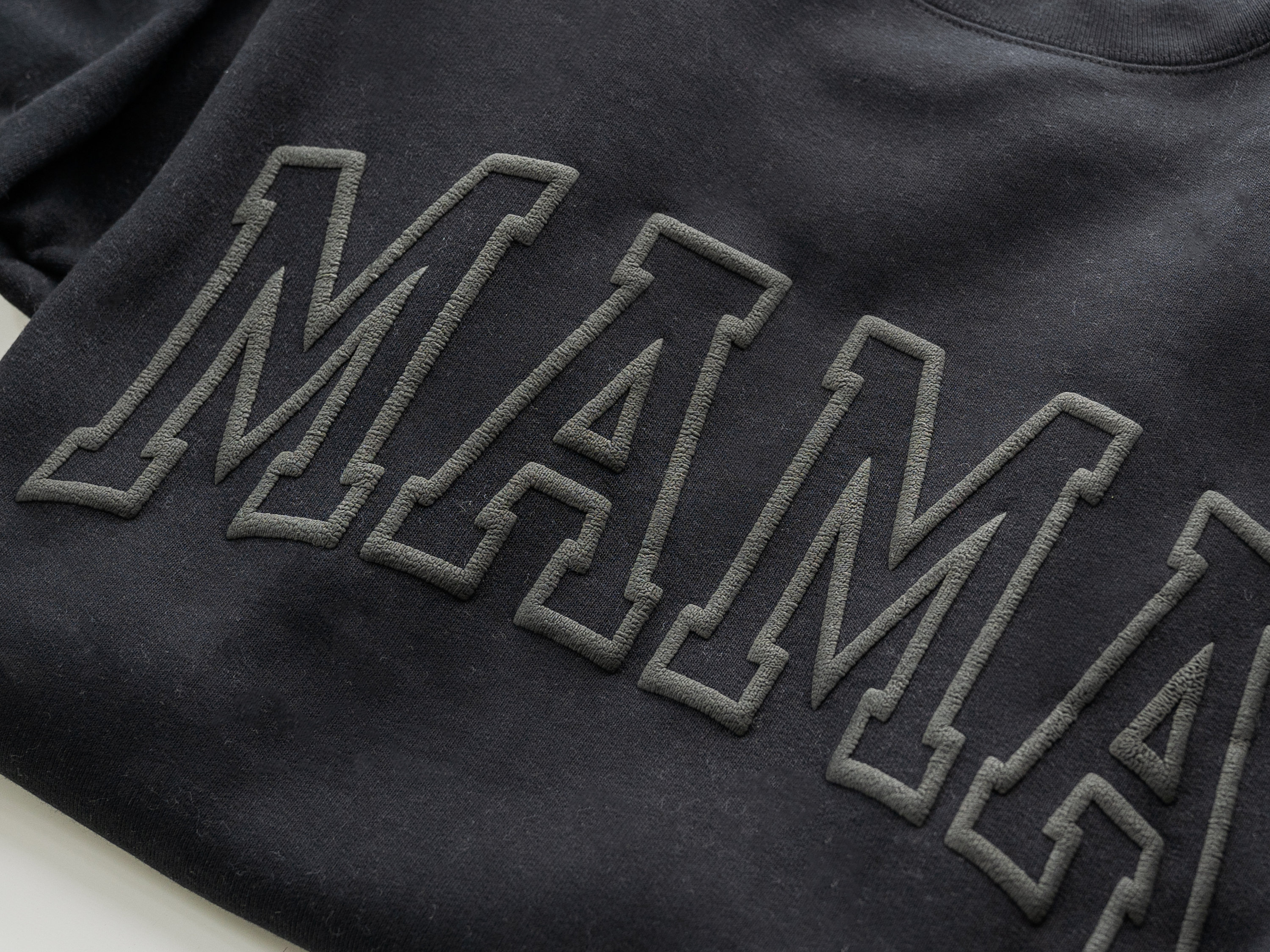 May include: Black sweatshirt with the word "MAMA" in large, outlined letters.