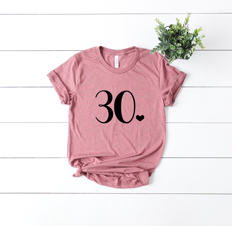 May include: A dusty rose colored t-shirt with the number 30 and a small heart printed on the front.