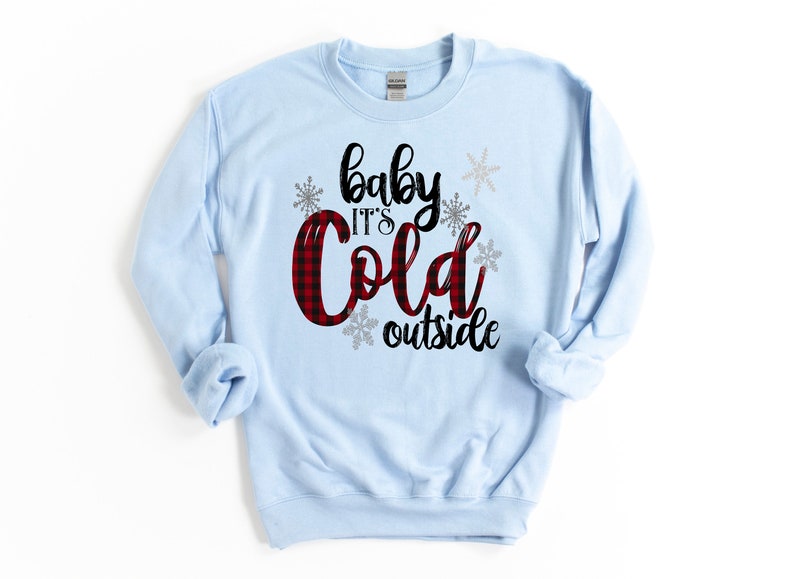 May include: Light blue sweatshirt with a black and red plaid design and the text "baby it's cold outside" in black lettering with silver snowflakes.