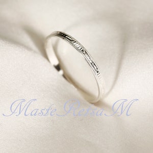 May include: A thin silver band ring with a delicate engraved design.