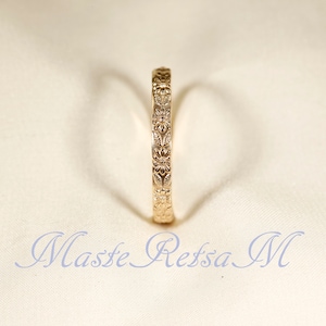 Puede incluir: Un anillo de banda de oro con un dise&ntilde;o floral. El anillo es simple y elegante.