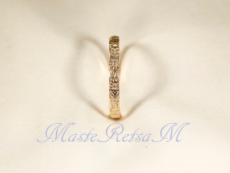 Puede incluir: Un anillo de banda de oro con un dise&ntilde;o floral. El anillo es simple y elegante.