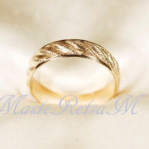 May include: A gold wedding band with a braided design.