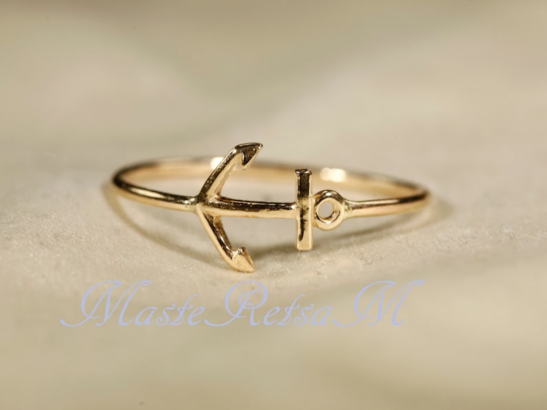 May include: A gold anchor ring. The anchor is a simple design with a small ring at the top.
