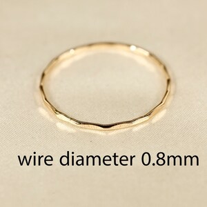 May include: A thin gold ring with a hammered texture. The wire diameter is 0.8mm.