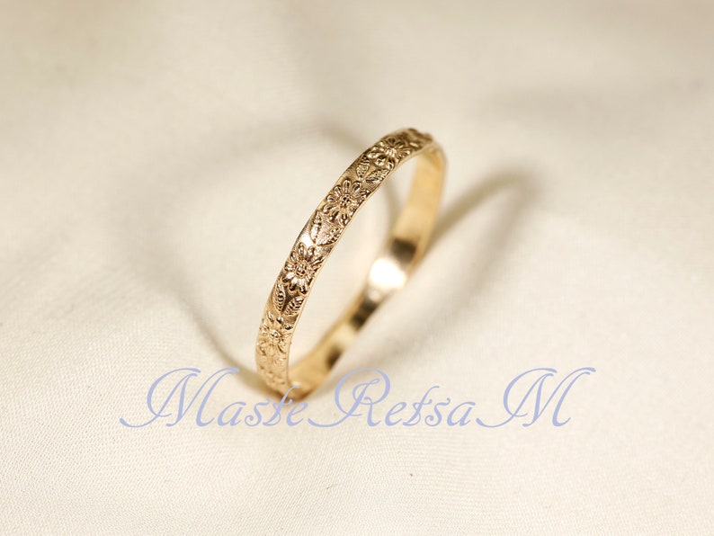 Puede incluir: Un fino anillo de oro con un dise&ntilde;o floral grabado alrededor de toda la banda.