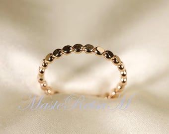 May include: A delicate gold ring with a beaded design. The ring is made of small, round beads that are evenly spaced along the band.