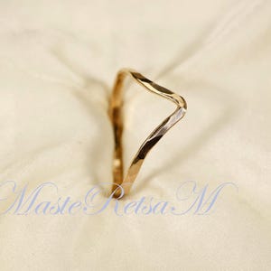 May include: A gold-toned hammered metal ring with a unique, asymmetrical, V-shaped design.