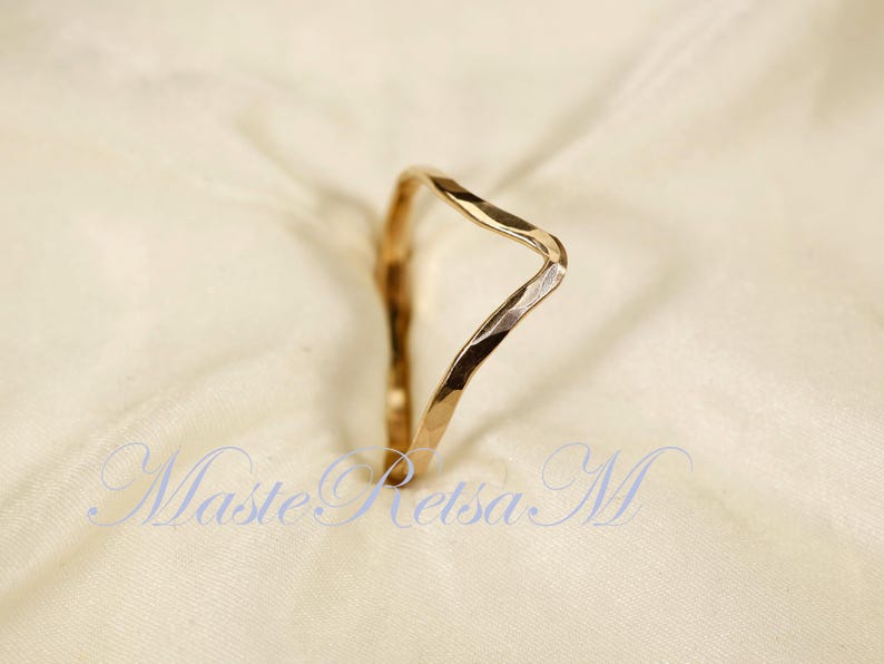 May include: A gold-toned hammered metal ring with a unique, asymmetrical, V-shaped design.