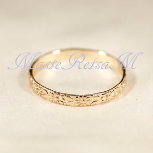 Puede incluir: Un anillo de banda de oro con un dise&ntilde;o floral. El anillo es simple y elegante.
