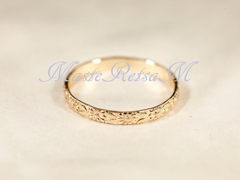 Puede incluir: Un anillo de banda de oro con un dise&ntilde;o floral. El anillo es simple y elegante.
