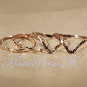 May include: Set of three gold-toned hammered metal rings. Two rings are simple bands, and one ring is a V-shaped band.