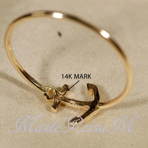 May include: A gold ring with an anchor design. The ring is marked "14K" on the anchor.