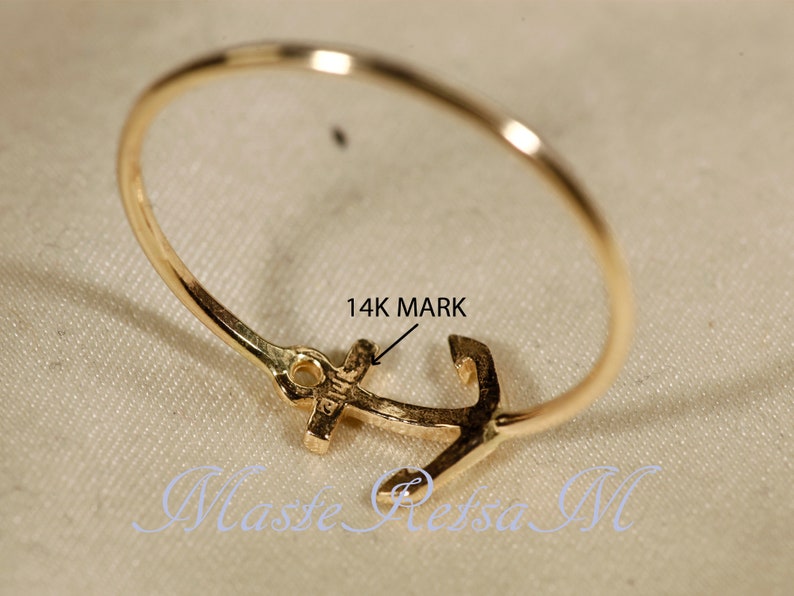 May include: A gold ring with an anchor design. The ring is marked "14K" on the anchor.