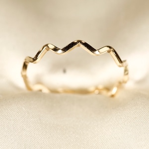 May include: A gold-colored ring with a zig-zag design.
