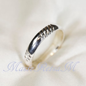 May include: A silver band ring with a textured design.