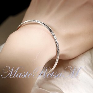May include: A silver bangle bracelet with a textured surface.
