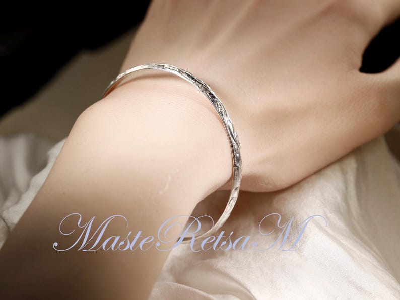 May include: A silver bangle bracelet with a textured surface.