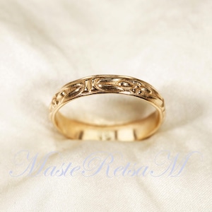 May include: A gold band ring with a detailed floral design.