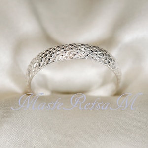 May include: A silver ring with a textured, woven design.
