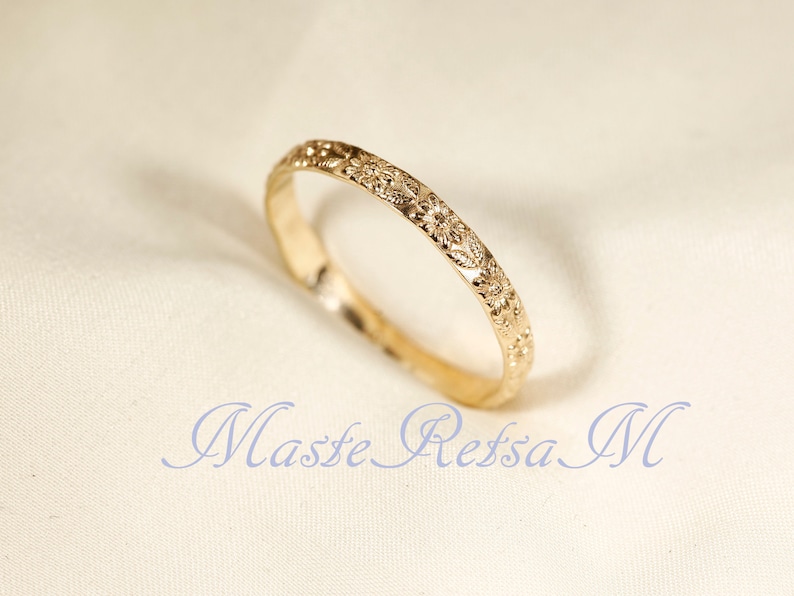 Puede incluir: Un anillo de banda de oro simple con un delicado dise&ntilde;o floral grabado alrededor de toda la banda.