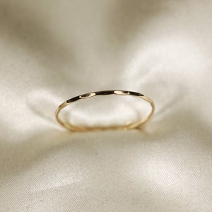May include: A thin gold band ring with a hammered texture.