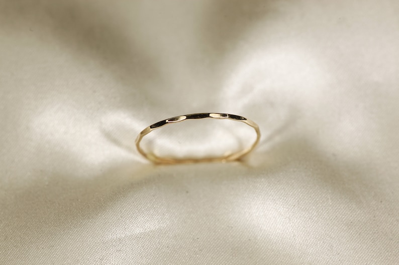 May include: A thin gold band ring with a hammered texture.