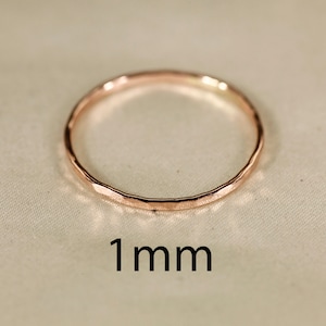 May include: A thin, hammered, rose gold ring with a 1 mm width.