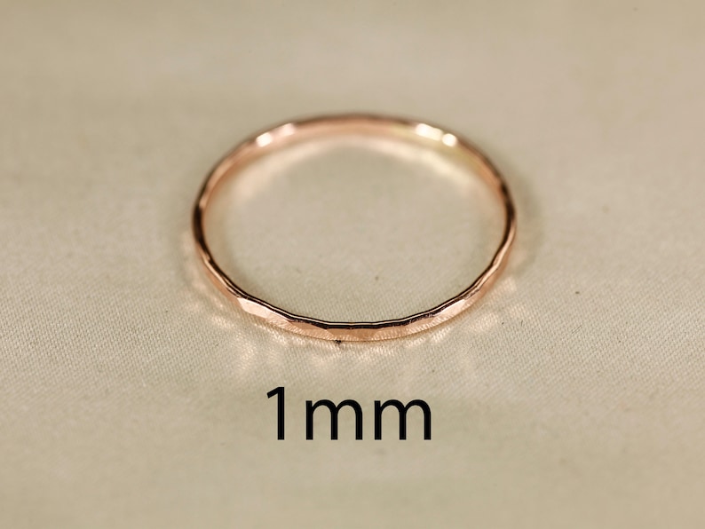 May include: A thin, hammered, rose gold ring with a 1 mm width.