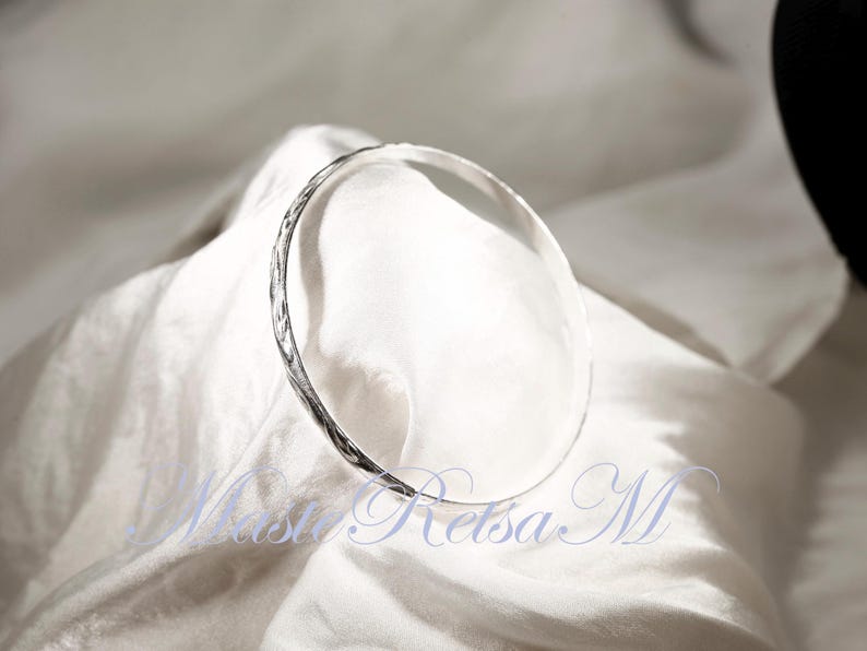 May include: A silver bangle bracelet with a textured surface.