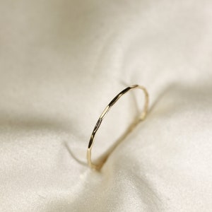 May include: A thin gold band ring with a hammered texture.