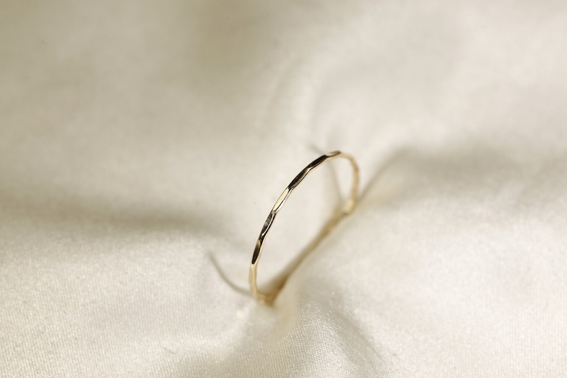 May include: A thin gold band ring with a hammered texture.