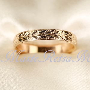 Pode incluir: Uma aliança de ouro com um delicado design de folhas.